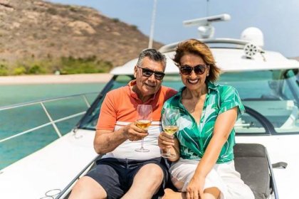 Rich senior couple relaxes with white wine on a yacht on a sunny day.