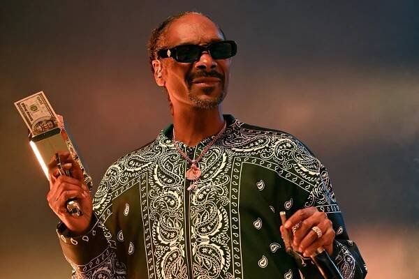 Snoop Dogg holding a money gun onstage.