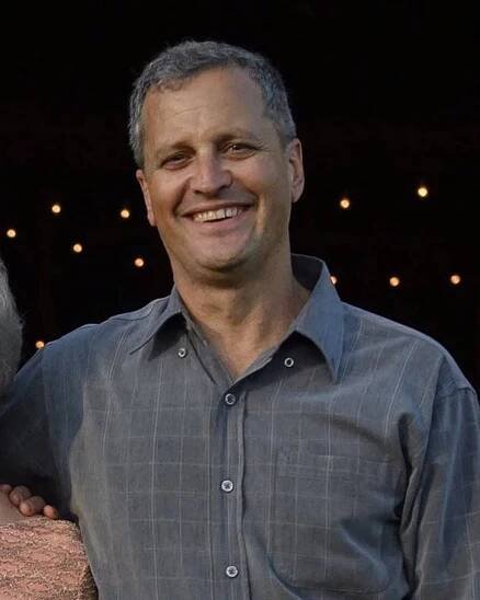 A smiling Marc Fogel, wearing an open-collared gray shirt.