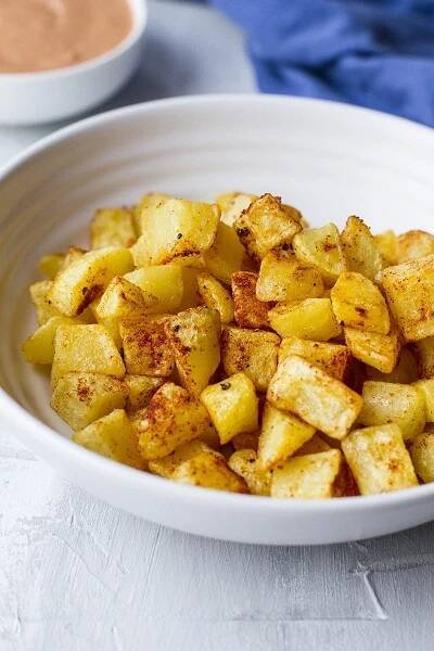 Large white bowl with cubed patatas bravas.