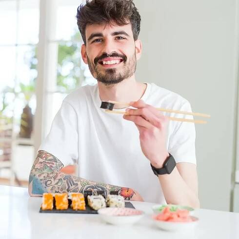 Happy man eating sushi roll
