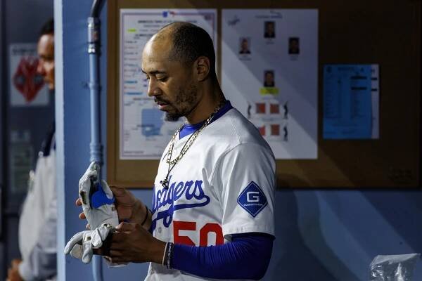 Dodgers shortstop Mookie Betts stares down at his batting gloves after flying out in the ninth inning.
