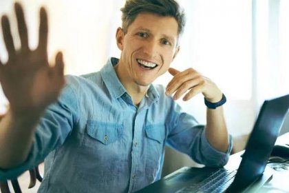 Portrét usměvavého šťastného muže sedícího u notebooku v kanceláři a zvedající se ruky ke kameře. — Stock fotografie
