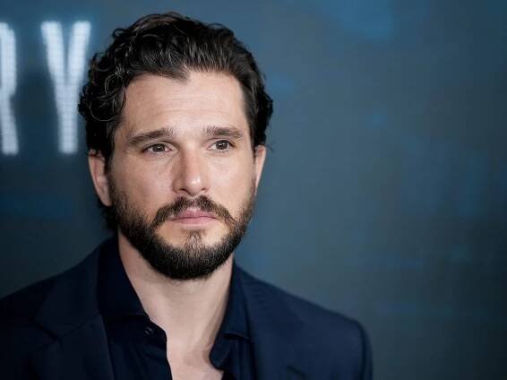 Kit Harington, who plays Jon Snow on "Game of Thrones," standing in front of a blue backdrop.