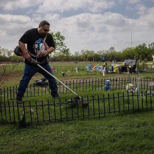 Javier Cazares uses a lawn trimmer to mow the grass at Jackie's grave. There are easter decorations around the grave. 