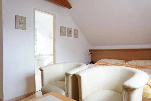two white chairs in a bedroom with a bed at Penzion u lázní in Velké Losiny