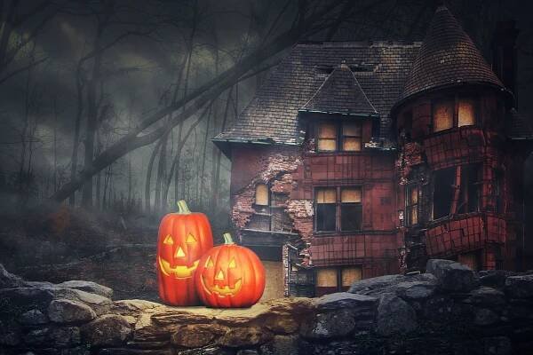Two jack-o'-lanterns outside an abandoned house in the woods