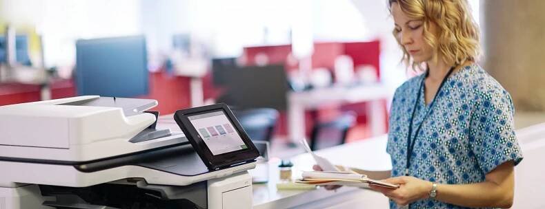 Zdravotnice s vytištěnými zdravotnickými záznamy před multifunkční tiskárnou HP LaserJet