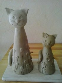 two ceramic cats sitting on top of a wooden table