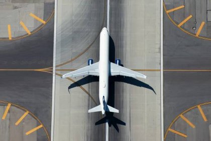 Obraz Aerial view of narrow body aircraft departing airport runway. Top down view of white unidentified airplane in the center of taxiway lines. Aviation industry.