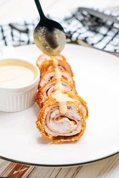 A plate with a roll of meat and sauce