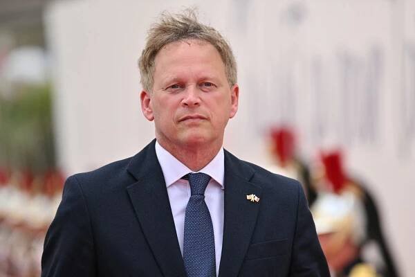 a man in a suit and tie stands in front of soldiers