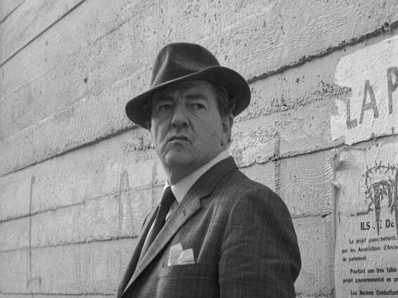 Rupert Davies as Maiget smokes pipe