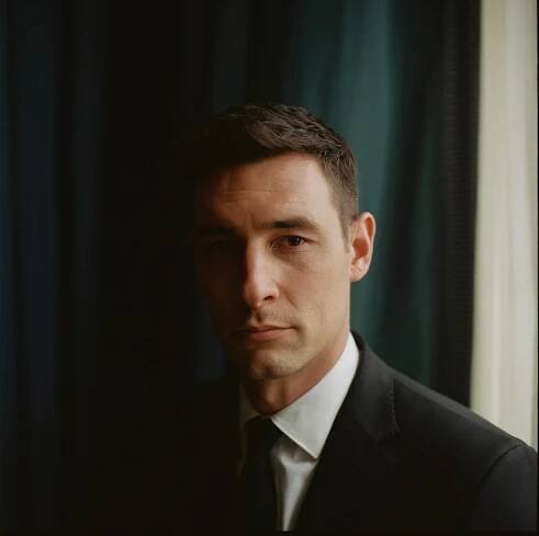 Frederick Szkoda as Luka Godek stands in front of an emerald green curtain in Season 1 of 'Fool Me Once'