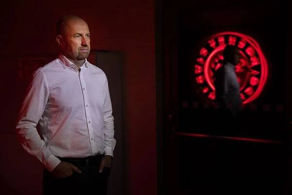 Jan Peterek v bílé košili vedle dveří s odrazem loga HC Oceláři Třinec