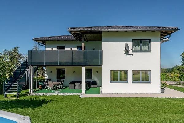 Modernes Einfamilienhaus in Österreich mit zusätzlicher Aufstockung, Balkon und gepflegtem Garten, ideales Beispiel für Hausumbauten und Wohnraumerweiterung.