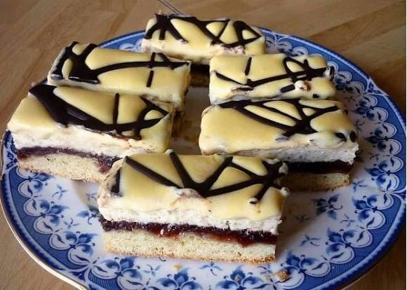 a blue and white plate topped with slices of cake covered in icing on top of a wooden table