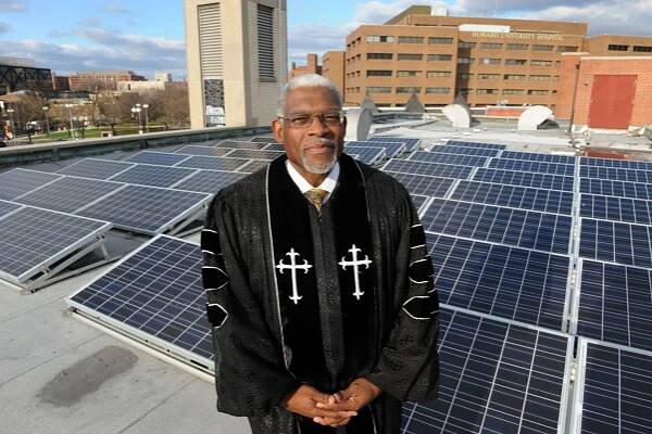 Rev. Dr. Earl Trent, Jr. standing in front of solar panels