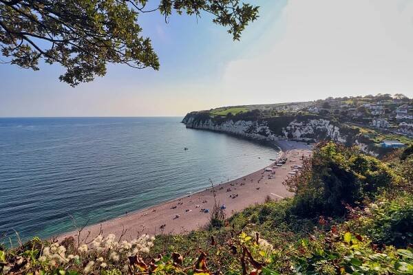 Beach in Devon, England, with boats and people.