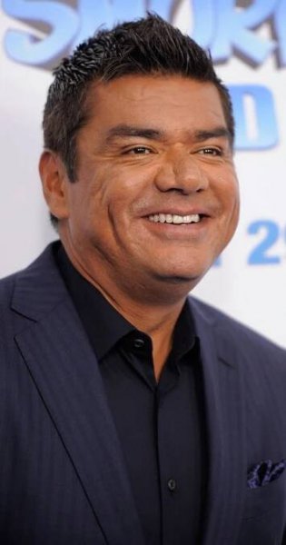 the smiling man is wearing a suit and black shirt