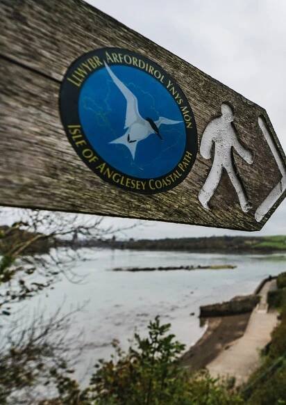 A wooden sign post for the Anglesey Coastal Path.