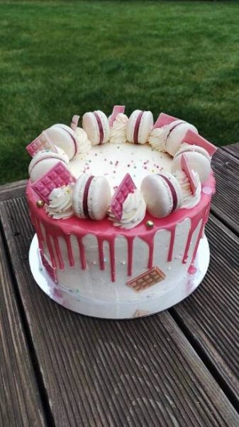 a cake sitting on top of a wooden table covered in white and pink icing