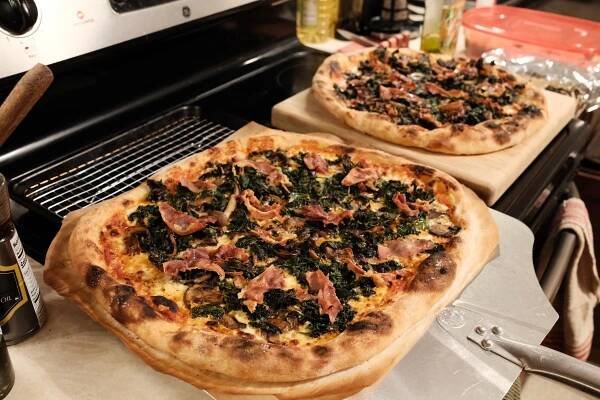Two pizzas cool on a stovetop.