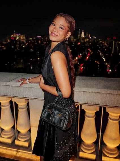 Storm Reid attends a Coach Gold event with a Coach bag in tow.