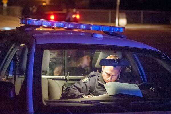 Const. Brad Chaput completes paperwork in his cruiser, suspending the license of a woman who failed a breath test. The woman sits in the back seat. When she is finally released, she chooses to walk home, after sacrificing her license and her car. The cost of the suspension for towing, impound fees, penalties and license reinstatement is roughly $1,430 -- and that's not counting the impact on her insurance premiums. (Richard McGuire Photo)