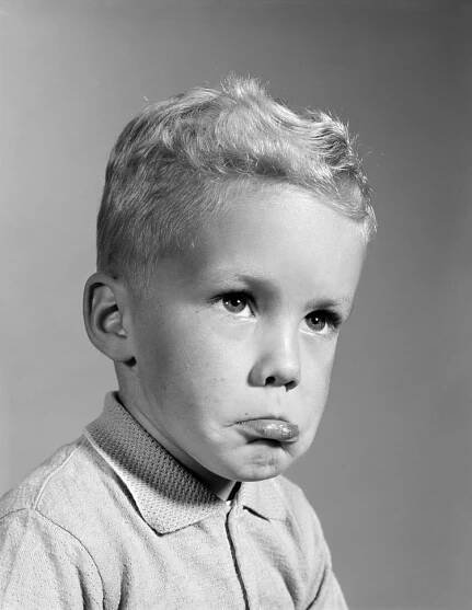 Blonde boy pouting, sticking out his lower lip, ready to cry.