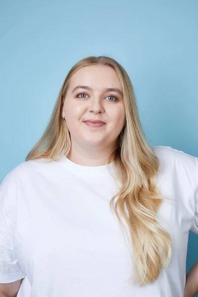 Woman with long blonde hair wearing a white t-shirt.
