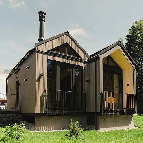 Modernes Holzhaus von WOLF Haus mit nachhaltiger Bauweise, gekennzeichnet durch große Fenster, minimalistisches Design und umgeben von grüner Landschaft.