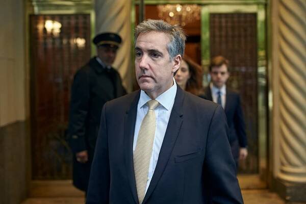 Michael D. Cohen, leaving his apartment building in Manhattan in a dark suit and blue shirt. 