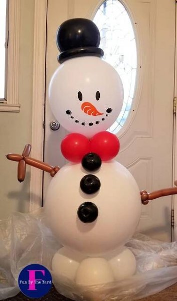 A snowman made out of balloons is standing in front of a door.