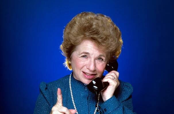 Dr Ruth Westheimer holding a phone to her ear in 1984