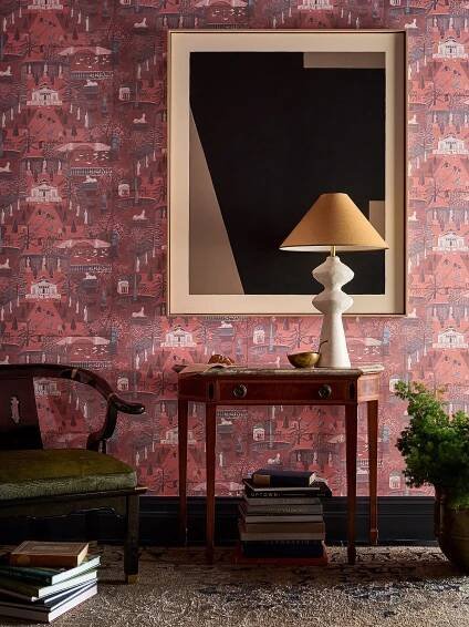 A bold, eclectic space with rich red wallpaper, a vintage console, and abstract art, warmly lit by a sculptural lamp.