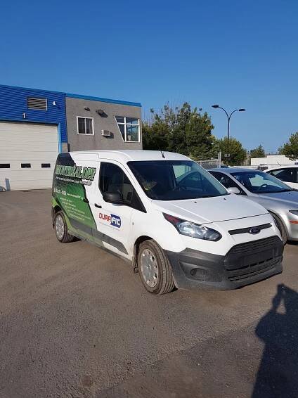 A white van is parked in front of a building.