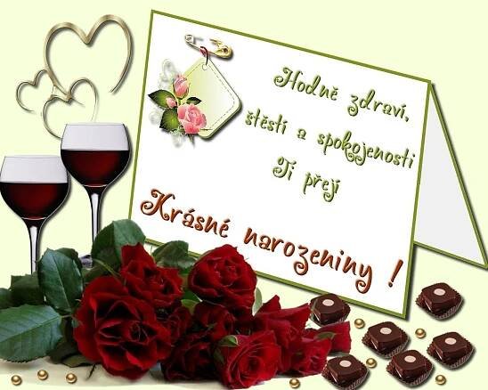 two glasses of red wine and some chocolates with roses on the table next to it