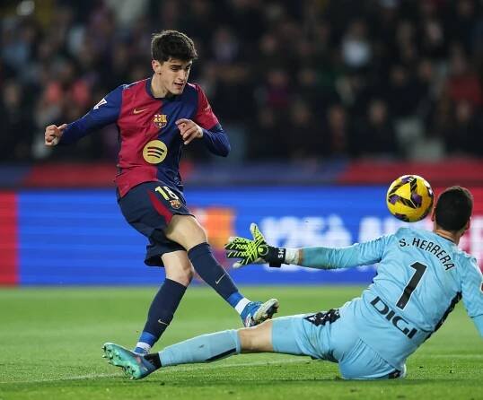 Pau Victor of FC Barcelona shoots at goal, while Sergio Herrera of CA Osasuna makes a save.