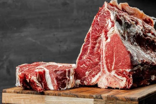 Raw T-bone steak cooking on stone table