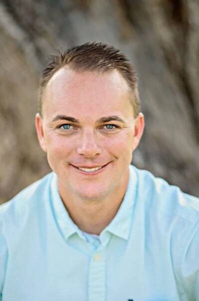A man in a light blue shirt is smiling for the camera.  Tim Shaw