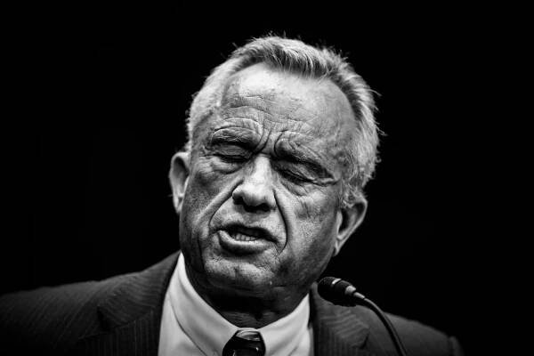 A black and white photo of Robert F. Kennedy Jr. talking with his eyes closed.