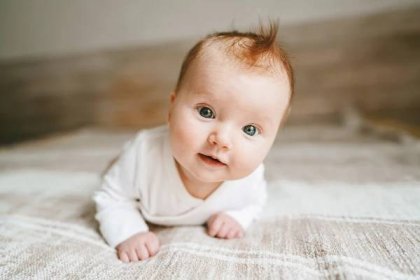 Plakát Cute baby ginger hair close up crawling on bed smiling adorable kid portrait family lifestyle 3 month old child