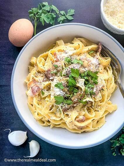 tagliatelle carbonara in bowl topped with parmesan and fresh parsley