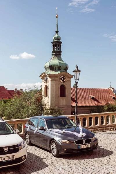 Automobil nevěsty stojící u Vršovického zámečku, na pozadí kostel sv. Mikuláše v Moskevské ulici