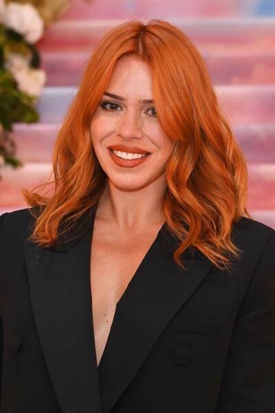 a woman with bright red hair is smiling for the camera while wearing a black suit