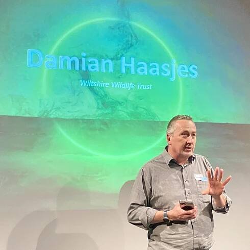 Damian Haasjes standing in front of a screen that reads "Damian Haasjes, Wiltshire Wildlife Trust"