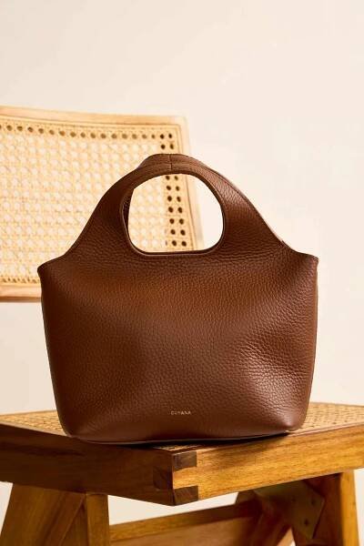 A Cuyana Mini System Tote displayed on a wooden chair with a wicker back