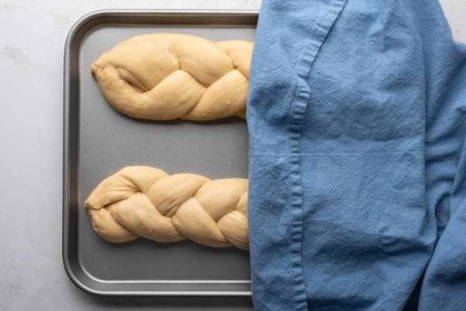 Braided dough on a baking sheet, covered with a towel 
