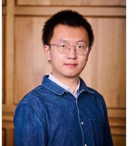 Yancheng Wang in front of wood paneling